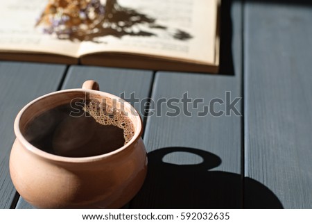 Cup of coffee, dry flowers and open book on wooden table. Romantic, retro backgroun, hard light