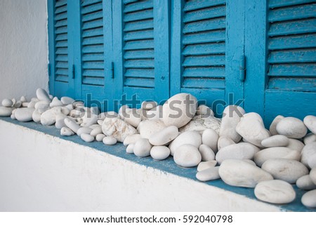 Round white stones on the window white houses with blue doors and window panes. Typical Greek, Sea House