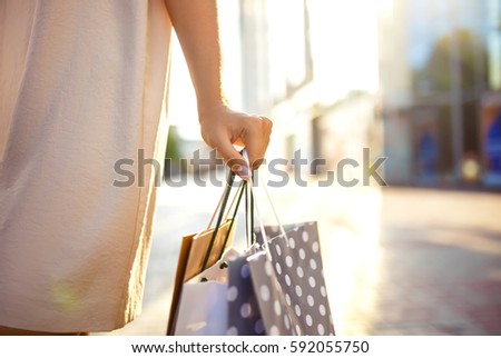 Beautiful girl with packages after shopping A picture of a group of happy friends shopping in the city. Girl walking around the city after shopping. good mood. Evening light. shopping concept


