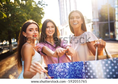 Beautiful girl with packages after shopping A picture of a group of happy friends shopping in the city. Girl walking around the city after shopping. good mood. Evening light. shopping concept


