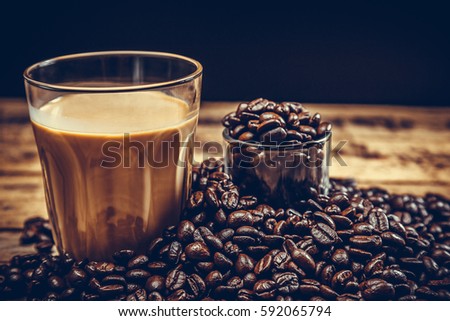 Coffee beans with hot coffee on old wood