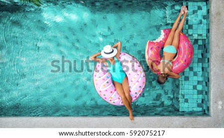 Two people (mom and child) relaxing on donut lilo in the pool at private villa. Summer holiday idyllic. High view from above. Royalty-Free Stock Photo #592075217