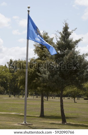Oklahoma state flag waving against a blue sky