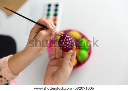 Female hands with brush paint easter holiday eggs, white background. Handmade decoration.