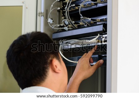 Close up hand of Asian computer engineer working at server room.Information technology connection concept.