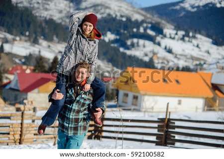 Young man holding his girlfriend on his shoulders. Against the backdrop of beautiful mountain scenery.