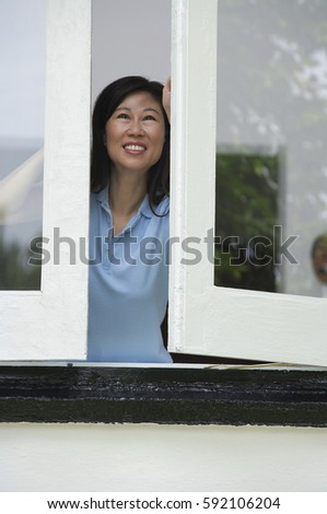 Woman opening windows, smiling