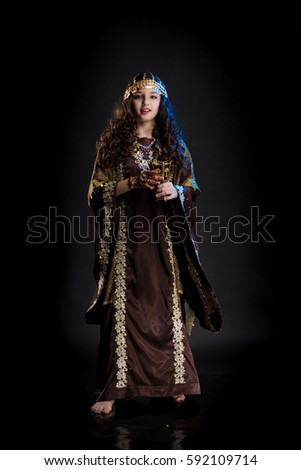 young girl with long hair in oriental dancer costume Khaleej posing and dancing on a black background in the scenic blue light