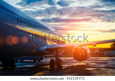 Airplane parked at the airport at dawn in the sky clouds sun Royalty-Free Stock Photo #592139771