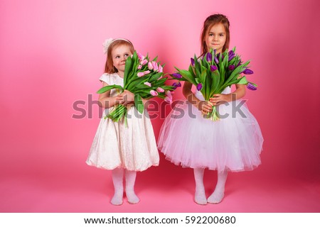 ?heerful and happy smiling girl holding bunch of tulips. Little girl with bouquet of flowers and rejoices to spring. 