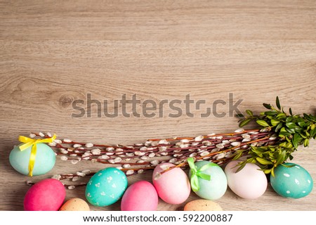 Easter composition of the branches, cakes, tulips colored eggs cooked for the holiday on the wooden background with free space for an inscription