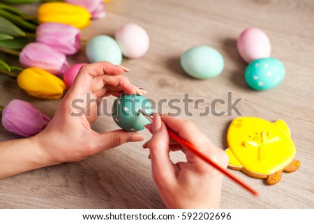 Hands on background wooden table girl paints the Easter eggs, preparing for the holiday, decor