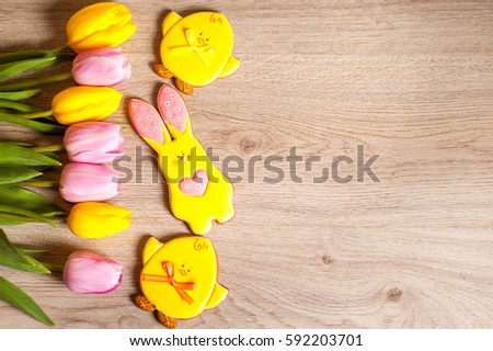 Easter composition of the gingerbread Easter bunny and chick , tulips,  cooked for the holiday on the wooden background with free space for an inscription