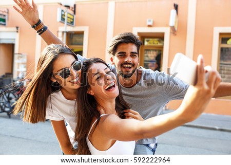 Group of happy young friends having fun on city street.Taking selfie. Royalty-Free Stock Photo #592222964