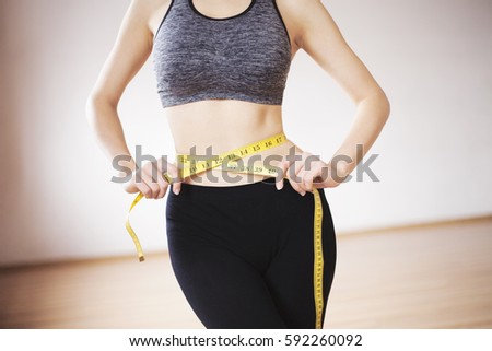 Athletic girl measuring figure in the gym.