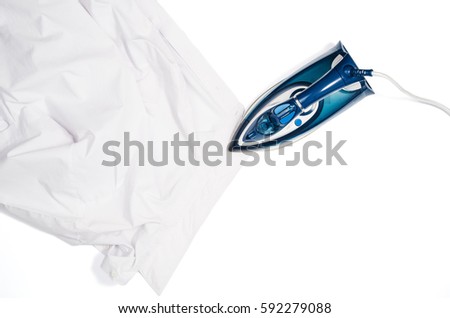 Female hand ironing clothes top view isolated on white background. Young woman with iron ironing man's shirt seen from above during housework. Blue iron on white table.