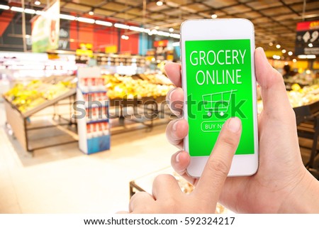 Woman hand click BUY NOW on mobile with blur supermarket background, Grocery online,  delivery concept.