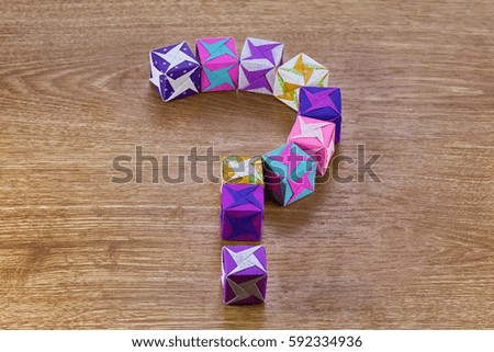 Origami paper colored cubes with whirligig on wood background
