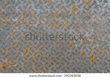 Old metal floor plate with diamond pattern and rusty background texture.