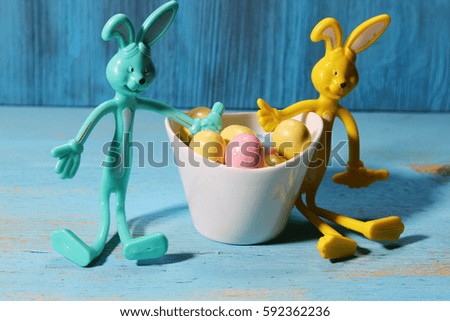 A bowl of Easter egg candy with two bunnies on a blue background