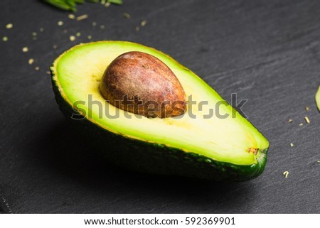 Half of fresh avocado on the black stone cutting board