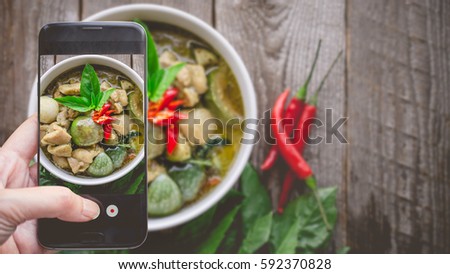 Taking a photo by Finger Pressing on Smartphone for Photograph Thai Chicken Green Curry. Image for Food Advertise or Social Media with Food Concept