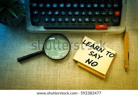 LEARN TO SAY NO wording on notebook with typewriter ,pen and 
magnifying glass on wooden table. Motivation and positive wishes concept
