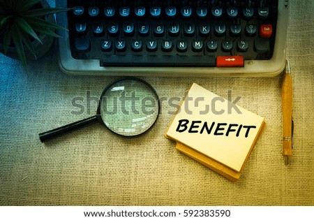 BENEFIT wording on notebook with typewriter , pen and magnifying glass on wooden table. Motivation and positive wishes concept