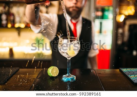 Bartender pouring alcoholic drink in glass Royalty-Free Stock Photo #592389161