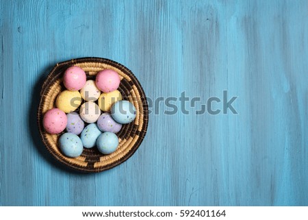 Top view of a basket of colored Easter candy with copy space on a blue background