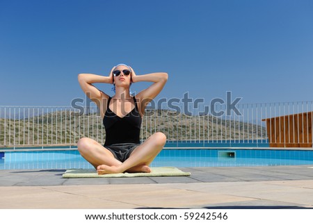 Young woman doing yoga exercise outdoors near swimming pool