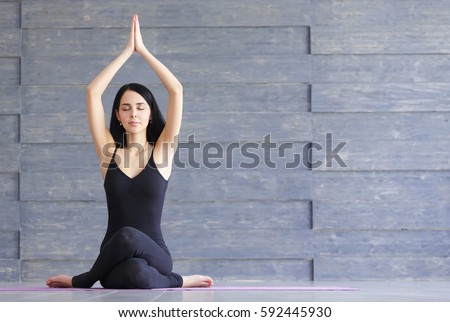 Yoga girl on fitness class background practicing nadi shodhana pranayama or Breathingin in gomukhasana asana or cow head pose Royalty-Free Stock Photo #592445930