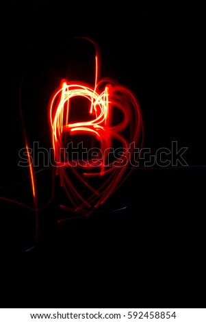 abstract red orange light painting on black background at night in the shape of heart bb