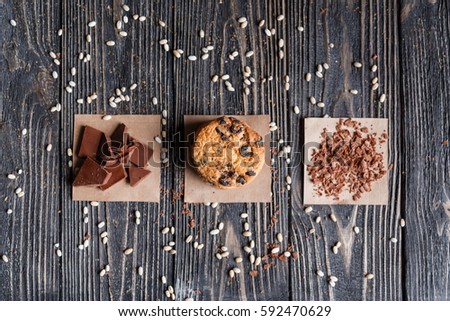 A stack of classic chocolate chip cookie and cereal chocolate on a napkin on a rustic dark table. Top view.
