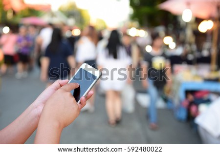 blurred photo and smartphone on people walking street market
