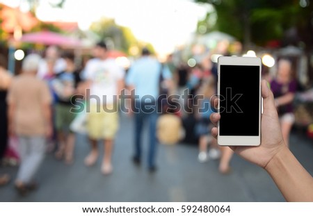 blurred photo and smartphone on people walking street market