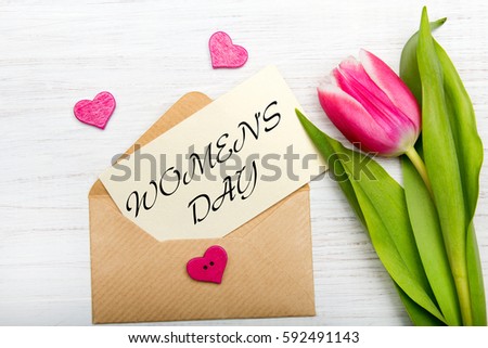 Women's day card. Tulip  and envelope on white wooden background