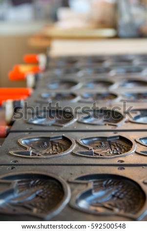 Close-up detail of multiple empty Taiyaki molds on a stove at a shop. Vertical orientation. Kyushu, Japan. Travel and cuisine concept.