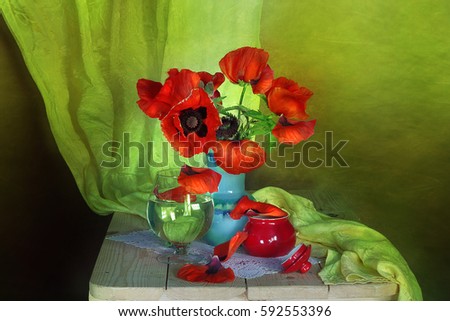 Still life of wild flowers. A bright bouquet of poppies in the basket . Color green and blue background.