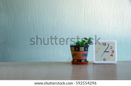 ivy plant and clock on the table against the background of blue wall