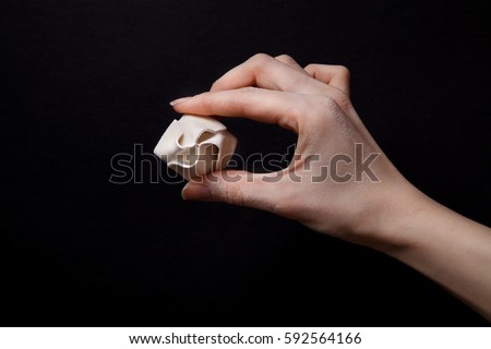 Woman hand holding dumpling (dim-sum) on black background. Side view with copy space