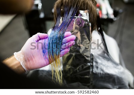 Man in gloves is dying long blue hair colorfull with brush. Beauty salon, Barber. Close-up. not recognized Royalty-Free Stock Photo #592582460