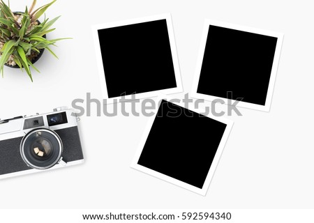 Film camera with blank picture frames are on top of white table. 