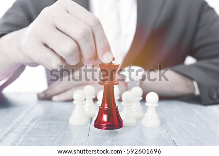 Business man moving chess figure with team behind - strategy or leadership concept Royalty-Free Stock Photo #592601696