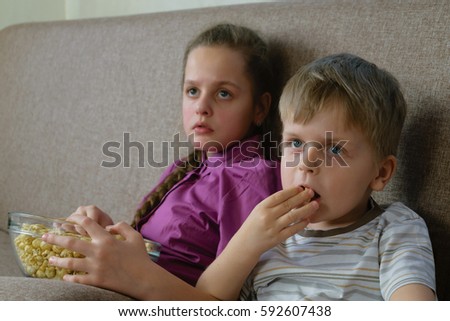 Boy and girl watching TV and eating popcorn