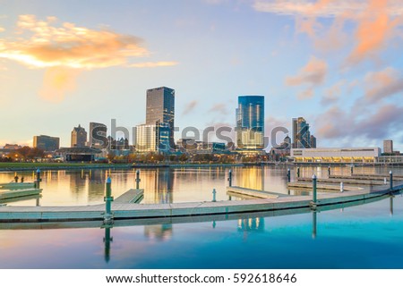 Milwaukee skyline at twilight with city reflection in lake Michigan and harbor pier.