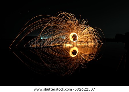 Firework showers of hot glowing sparks from spinning steel wool on the ground. Light painting. (Long Exposure)