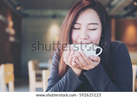 Closeup image of Asian woman smelling and drinking hot coffee with feeling good in wooden vintage cafe