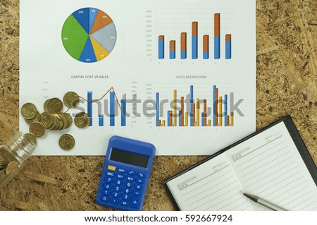 business conceptual with graph, calculator and coins on the wooden desk. 