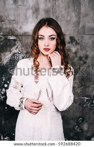 portrait of a beautiful woman with brunette hair in a unique dress on a gray background. Ukrainian style. modern Ukrainian national clothes